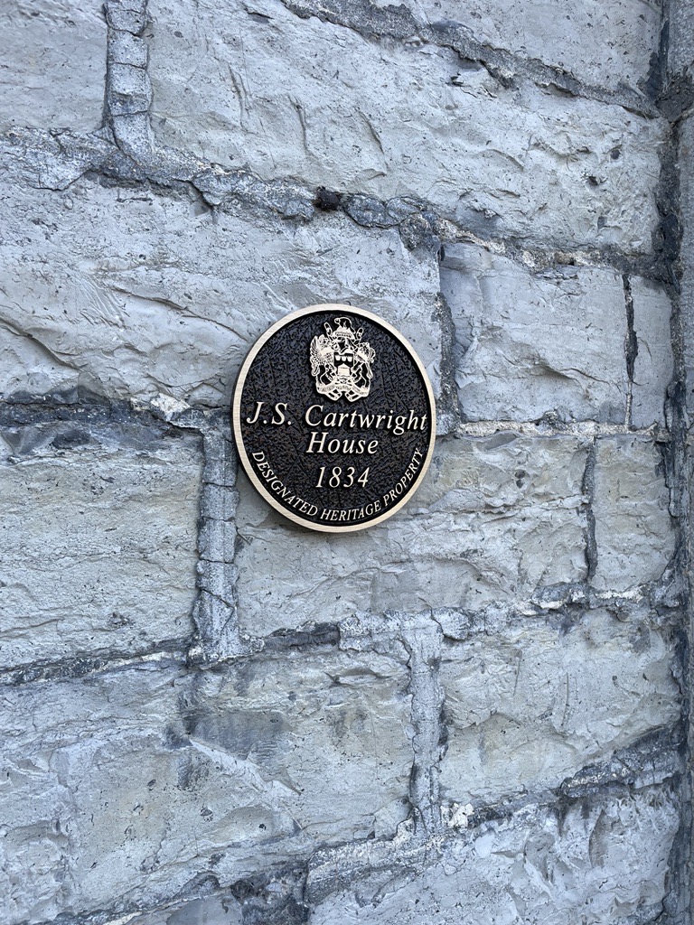 Photo of a heritage plaque on the exterior of a stone wall that reads, "J.S Cartwright House 1834, Designated Heritage Property".