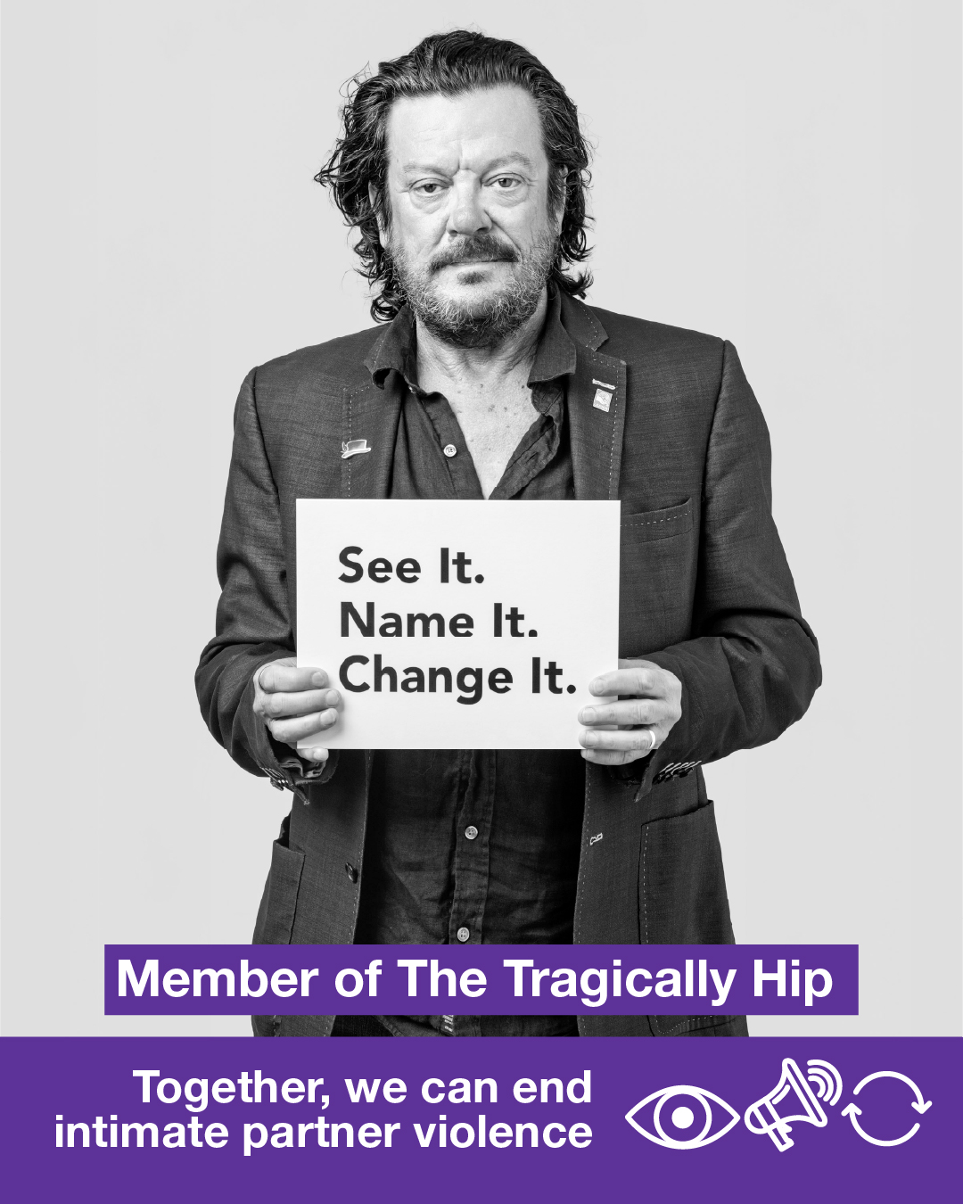 A black-and-white photo of a member of The Tragically Hip holding a sign that says See It. Name It. Change It. Together, we can end intimate partner violence.