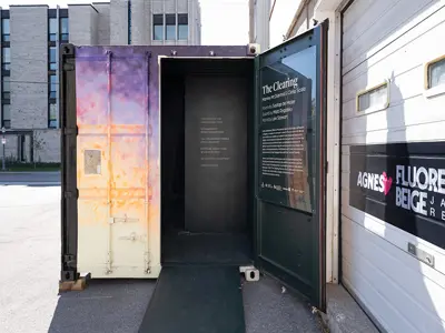 An open shipping container that houses the art project 'The Clearing', located on Queens campus.