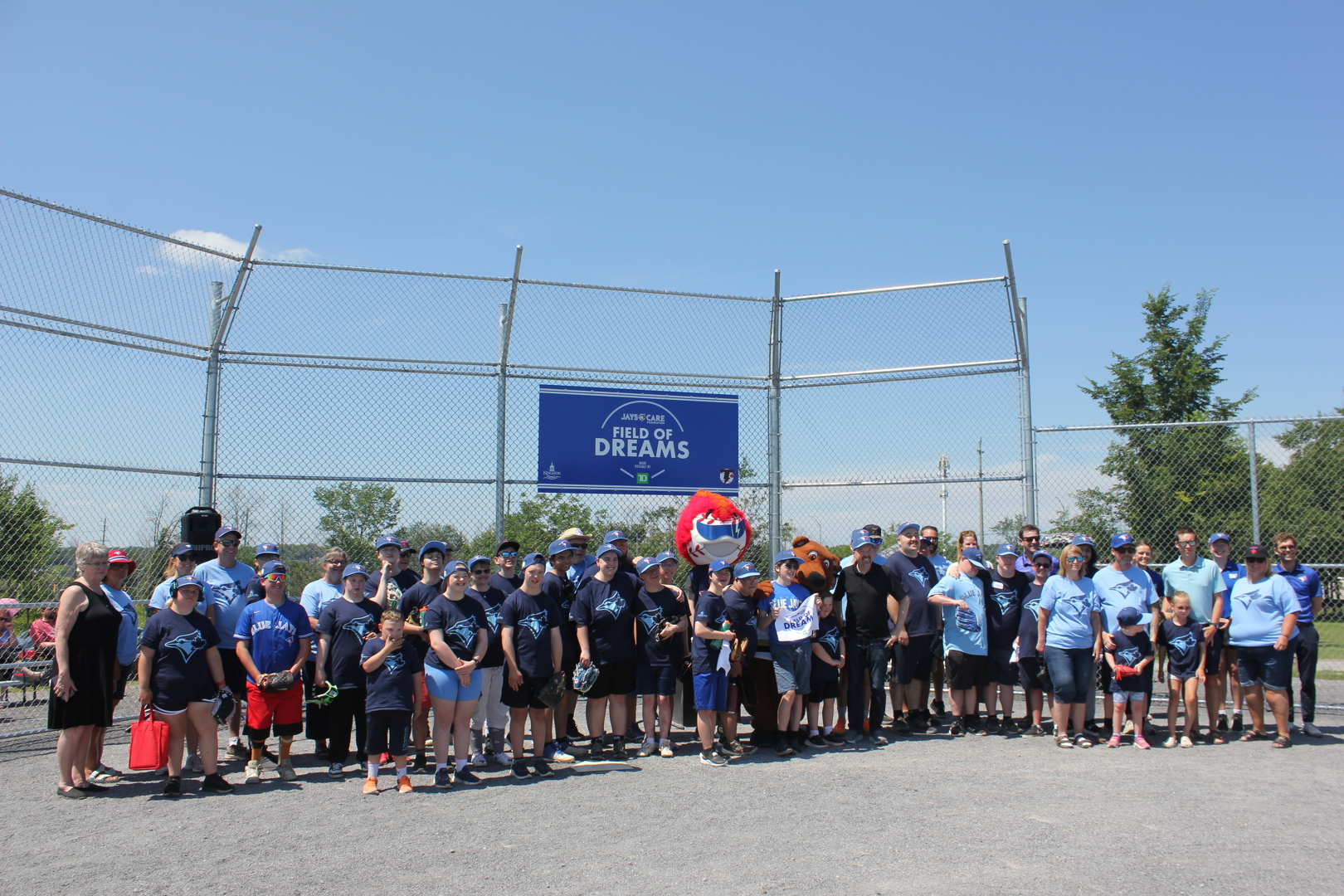 Members of the Kingston Thunder Challenger team, along with Mayor Paterson and representatives from Jays Care Foundation gather in front of the backstop at the new Jr. Baseball Diamond at Woodbine Park