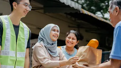 Multiple people helping provide food to a man