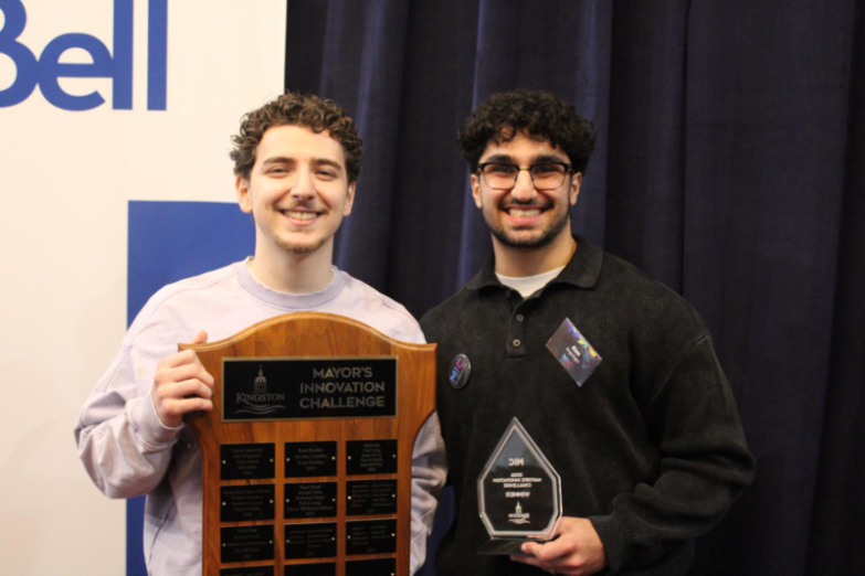 Two members of BRIGHTSIGHT, member on the left is holding the Mayor's Innovation Challenge plaque, member on the right is holding the Mayor's Innovation Challenge trophy.