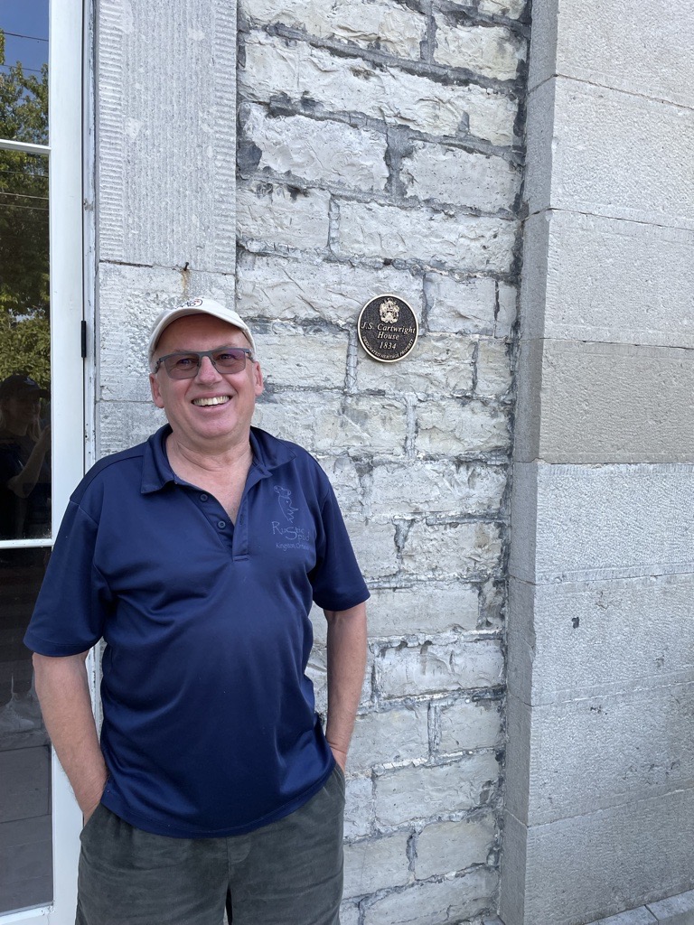 March Shaw standing beside Heritage plaque on 221 King St E